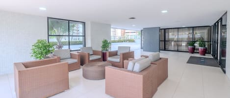 Un espacio interior amplio con mobiliario de mimbre, ventanas grandes y plantas en macetas.