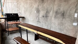 A rustic dining area with a long wooden table and benches, set against a concrete wall. - Relaxation and comfort in a private apartment (Roldanillo)