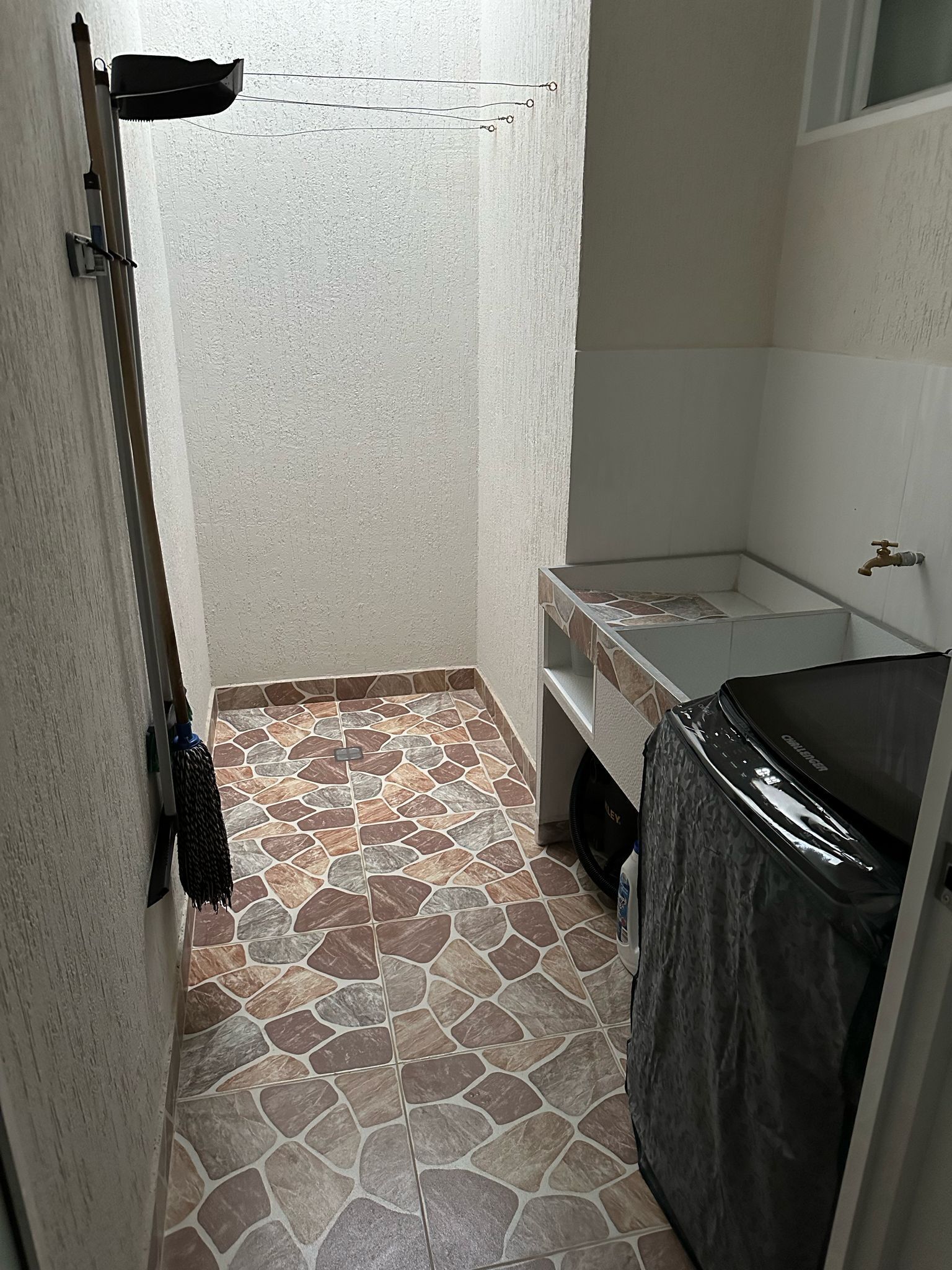 Ein Badezimmer mit Steinboden, einem weißen Waschbecken und einer schwarzen Badewanne.