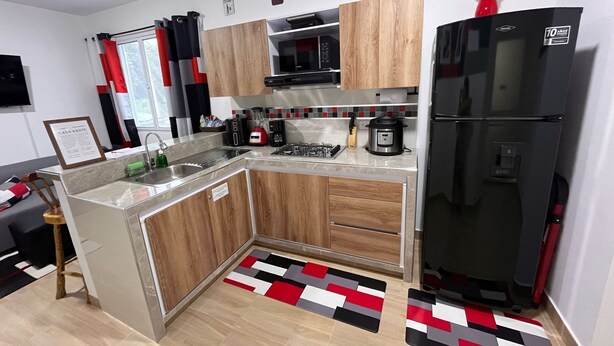 A modern kitchen with wooden cabinets, a black refrigerator, a stove, and a sink. - Relaxation and comfort in a private apartment (Roldanillo)