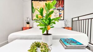 A bedroom with a bed, a potted plant with a lemon, a book, and a painting on the wall. - Loft Jason | Relaxing Lake Conroe Getaway (Montgomery)
