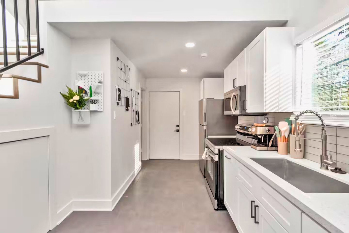 A modern kitchen with white cabinets, stainless steel appliances, and a countertop with kitchen tools.
