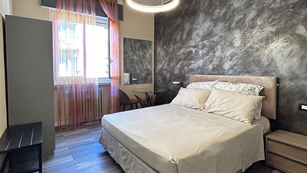 A bedroom with a large bed, a desk, and a chair.