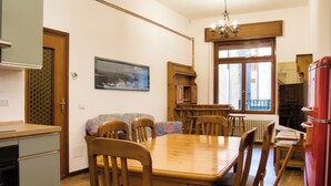 Een eethoek met een houten tafel en stoelen, een bank en een rode koelkast.