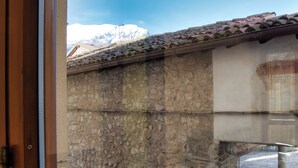 Un muro de piedra con tejado de baldosas y una vista despejada de una montaña al fondo.