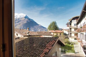 A view of a mountain with a snow-capped peak, a tiled roof, and a building with balconies. - Cuor di Barzio P2 - Two Bedroom Apartment, Sleeps 5 (Barzio)