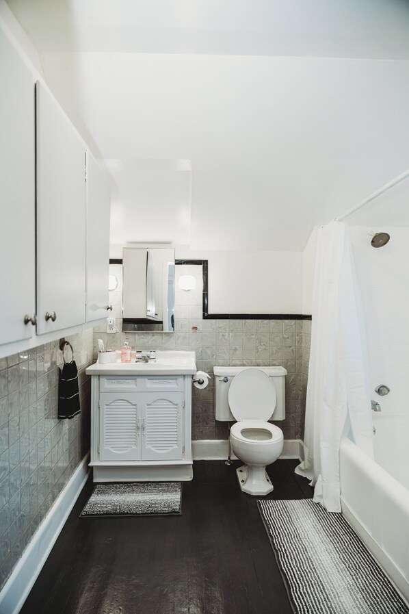 Un baño con inodoro, lavamanos, espejo y cortina de ducha.