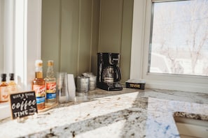 Una encimera de cocina con cafetera, azúcar, tazas de café y un cartel que dice 'Coffee Time'.