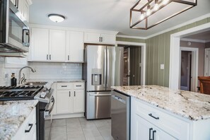 A modern kitchen with white cabinets, stainless steel appliances, and a granite countertop.