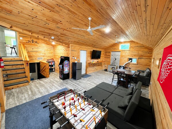 A cozy room with a foosball table, a sofa, a TV, and a fireplace.