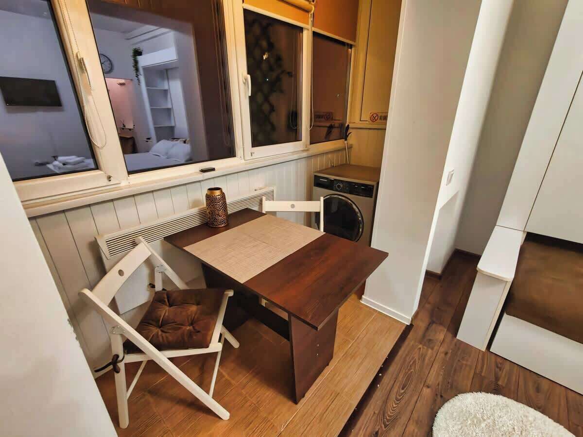Una cucina compatta con un tavolo e sedie in legno, un forno a incasso e una finestra con persiane.