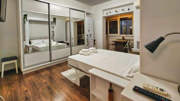 Quarto moderno com um espelho grande, uma cama, uma escrivaninha e uma cadeira.