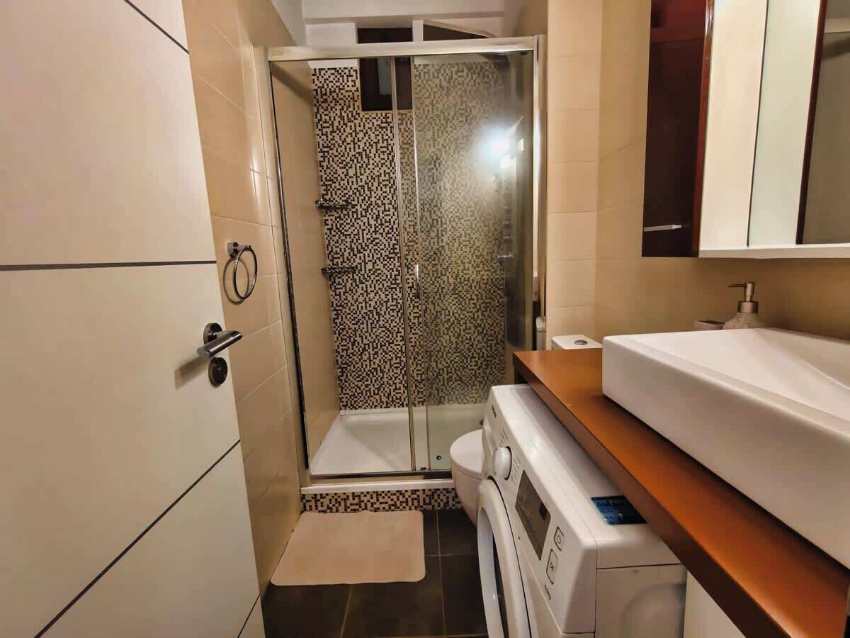 Ein kleines Badezimmer mit Dusche, Toilette und Waschmaschine.