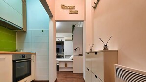 Uma cozinha moderna com armários brancos, forno embutido e piso de madeira.