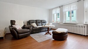 Ein Wohnzimmer mit braunem Ledersofa, einem kleinen runden Tisch und einem Holzfußhocker.