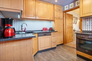 A kitchen with wooden cabinets, a Bosch dishwasher, a red coffee maker, and a Bosch oven.