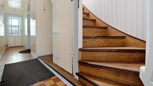 Eine Treppe mit Holzboden und weißen Wänden, die zu einer Tür mit Fenster führt.