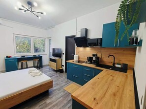 A modern bedroom with a bed, a desk, and a kitchenette. - Botev Apartment | Design studio 10 | Old Town (București)