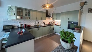 Une cuisine moderne avec des meubles de couleur vert clair, un plan de travail noir et un îlot central.