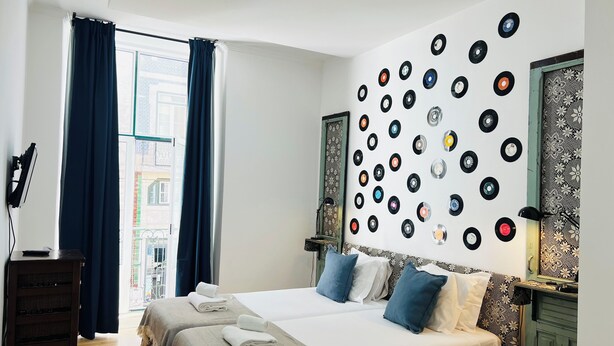 A bedroom with a bed, pillows, and a wall decorated with vinyl records. - Lisbon Heart (Lisbon)