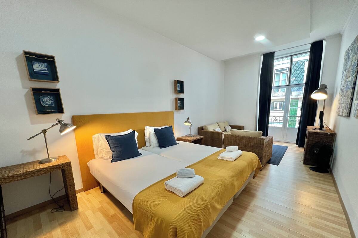 Une chambre d’hôtel avec deux lits, un coin salon et une grande fenêtre.