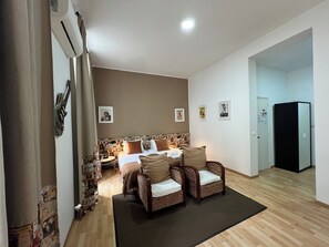 A hotel room with a bed, two wicker chairs, a small table, a desk, and a refrigerator. - Lisbon Heart  (Lisbon)
