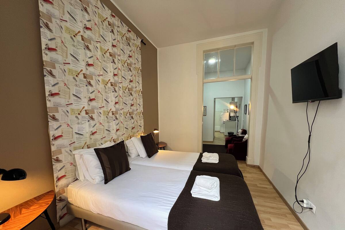 Une chambre d’hôtel avec deux lits, une télévision et un bureau.