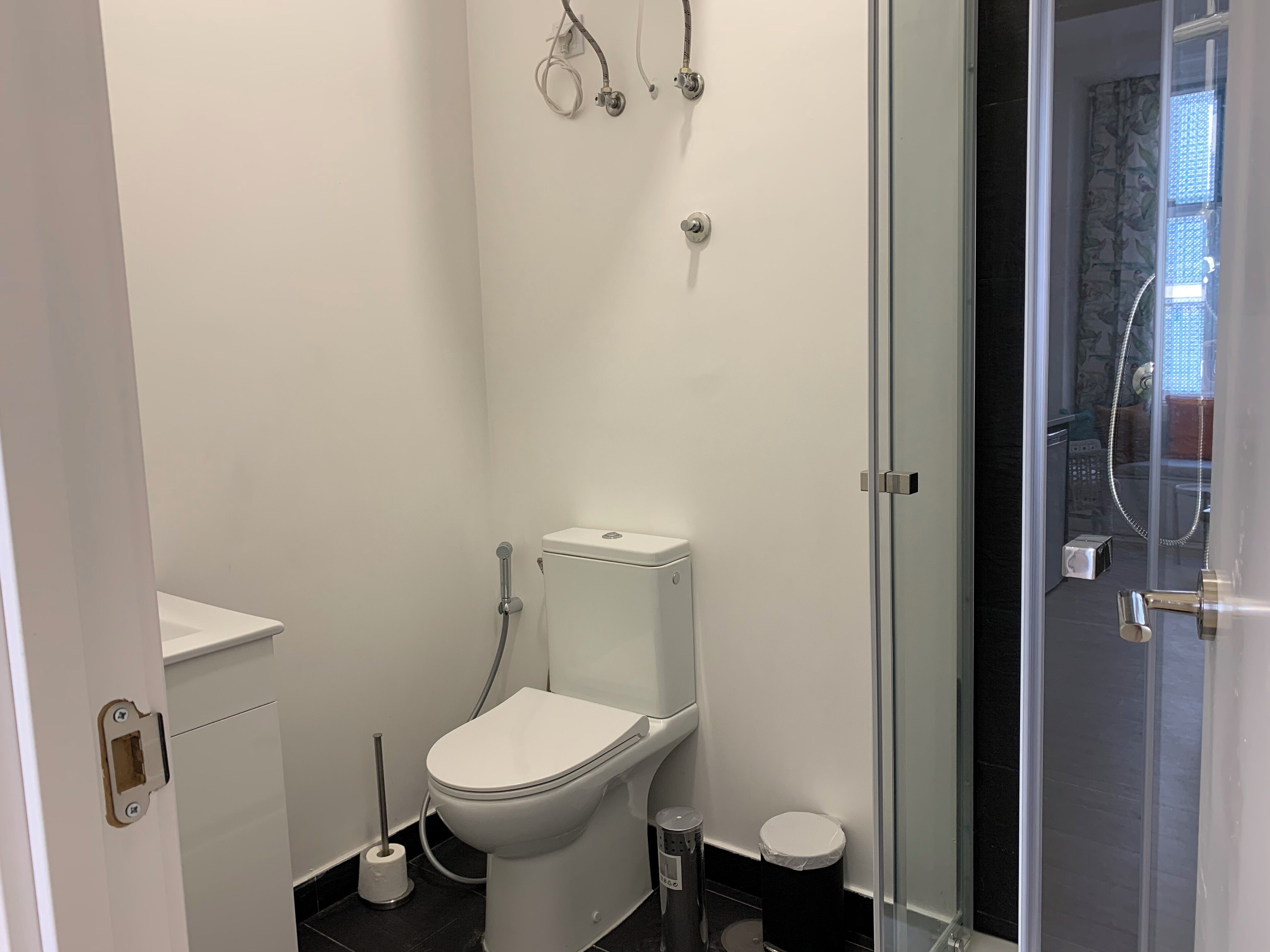 A modern bathroom with a toilet, bidet, and glass shower enclosure.
