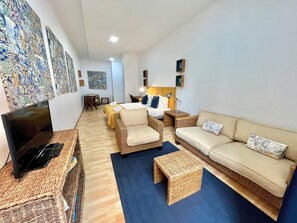 A modern living room with a TV, wicker furniture, a sofa, and a dining area. - Lisbon Heart  (Lisbon)