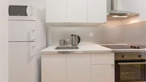 A modern kitchen with white cabinets, a built-in microwave, a kettle, and a stove. - Lisbon Heart (Lisbon)