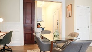 Un coin repas avec une table en verre, quatre chaises grises et un tapis.