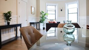 Un coin repas avec une table en verre, des chaises en cuir, une plante en pot et un vase décoratif en verre.