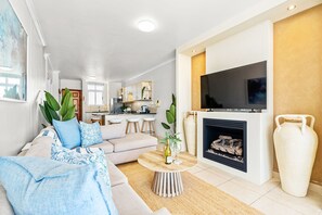 A modern living room with a sofa, coffee table, fireplace, and TV. - Atlantic Terraces 19 (Cape Town)