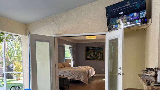 Una habitación amplia con una cama, televisión y comedor con una mesa de madera original.