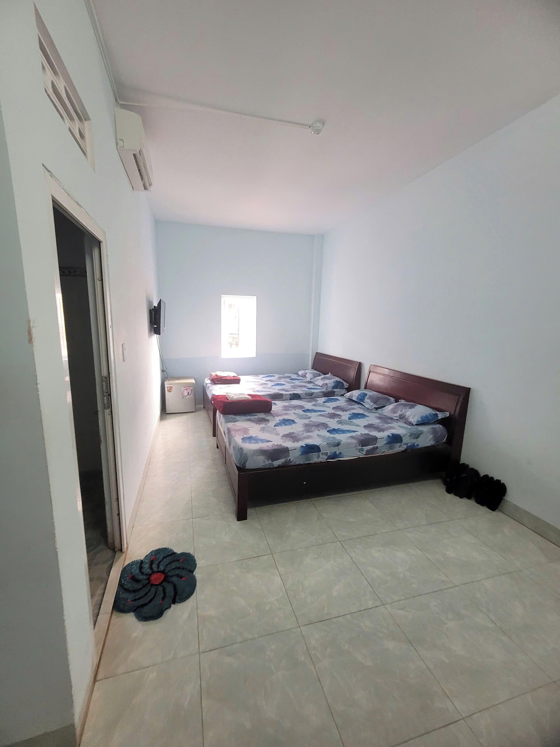Un dormitorio con cama, mesita de noche, ventana y puerta.