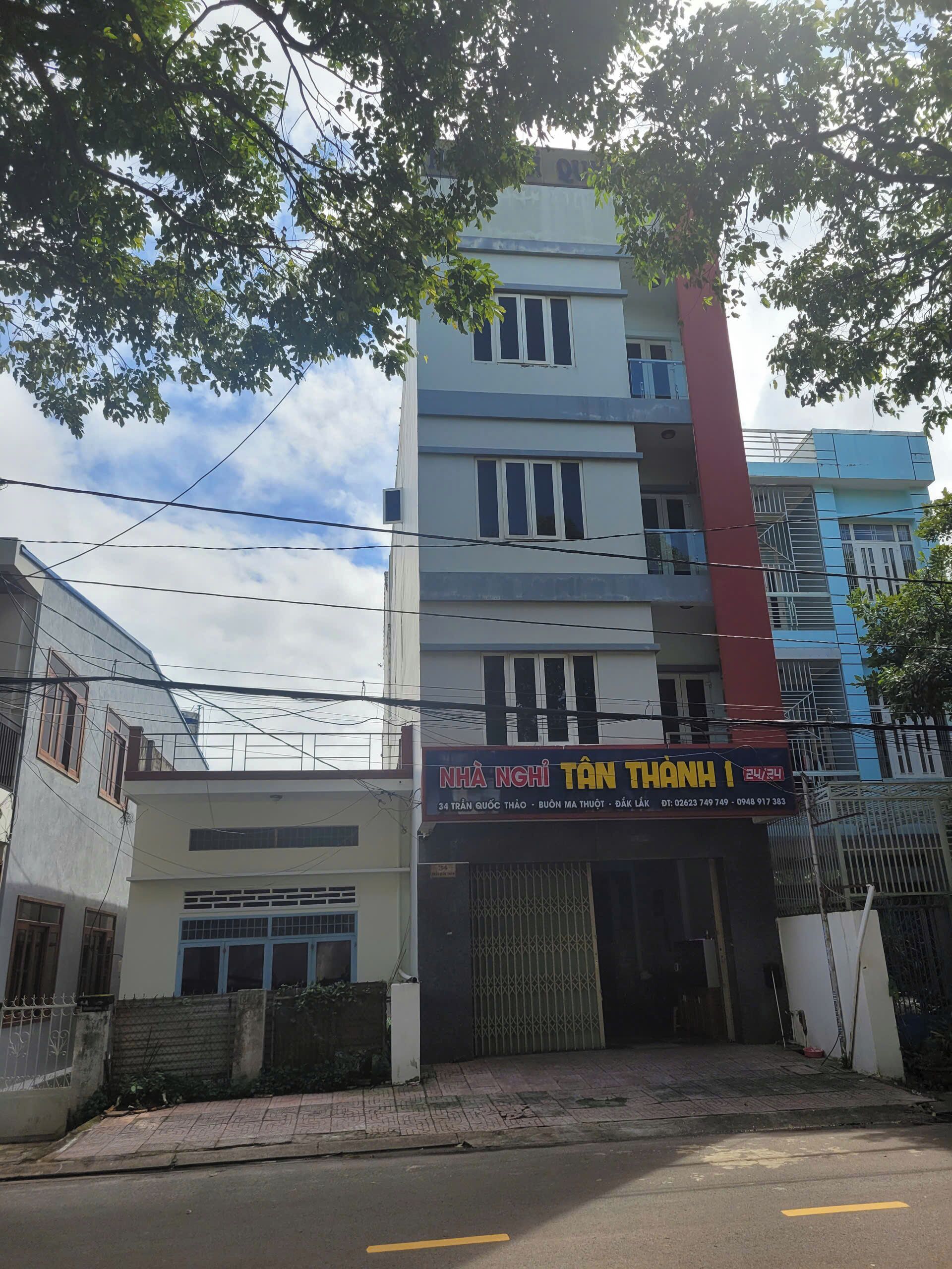 A multi-story building with a storefront labeled "NHÀ NGHI TÂN THANH" and contact information.