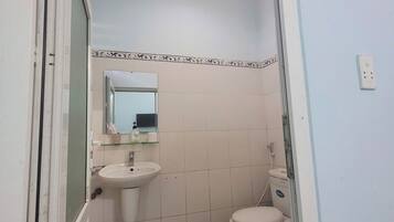 A bathroom with a sink, toilet, and mirror.