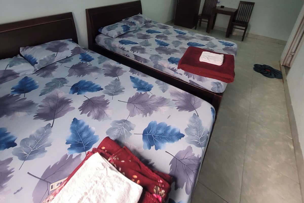 Una habitación con dos camas, una mesa, sillas, un ventilador y piso de baldosas.
