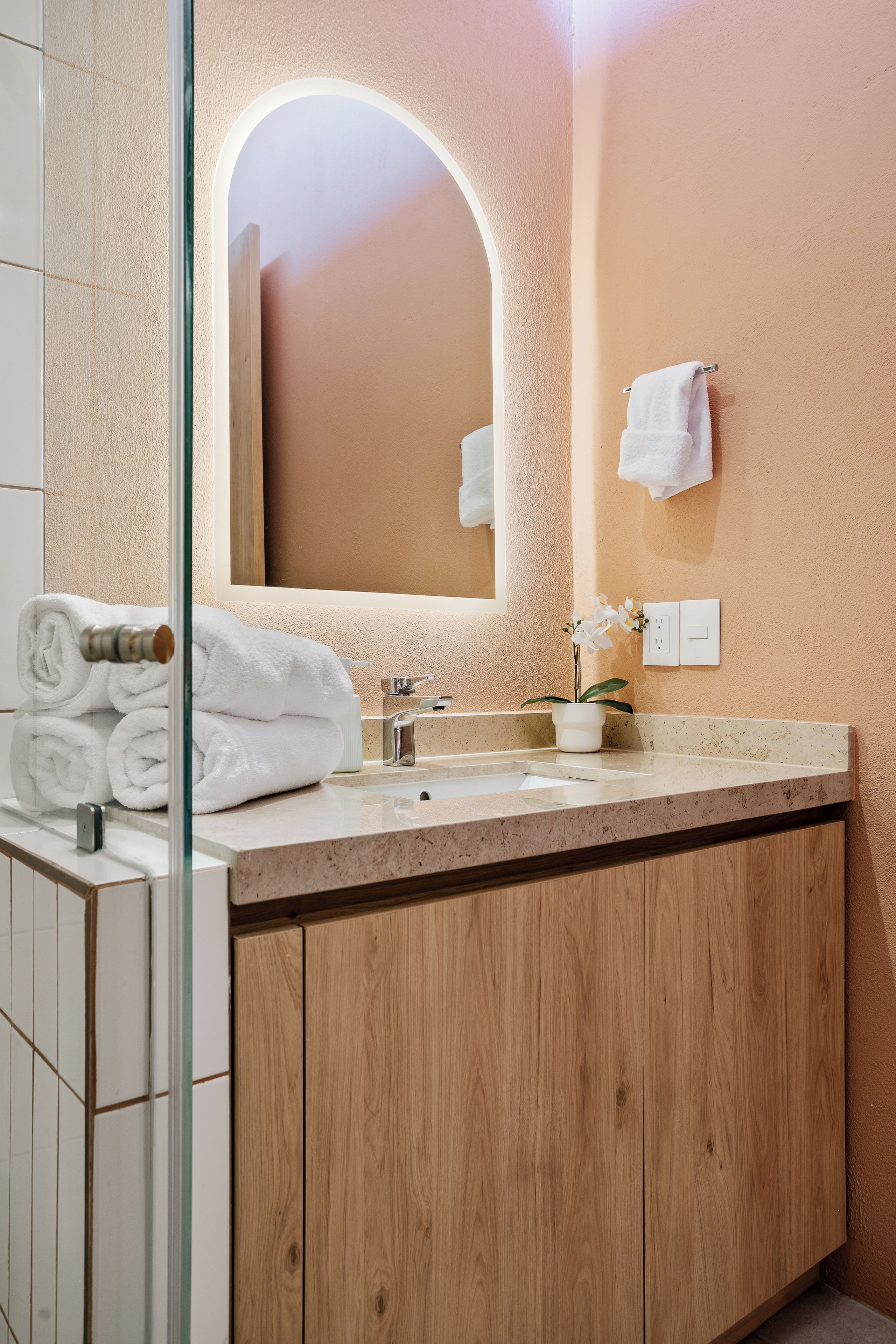 A bathroom with a wooden vanity, a sink, a mirror, and a towel rack.