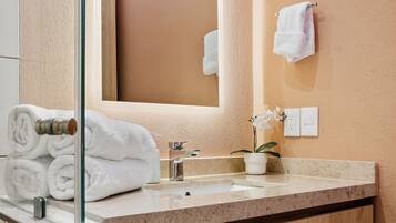 A bathroom with a wooden vanity, a sink, a mirror, and a towel rack.