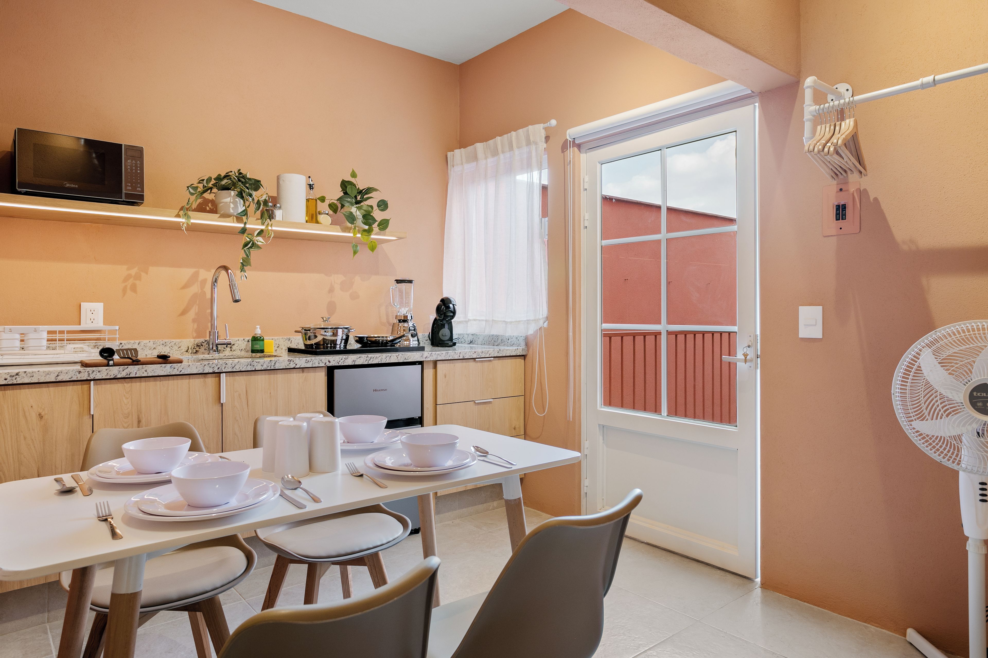 A modern kitchen with a dining table set for four, a microwave, and a variety of kitchen appliances.