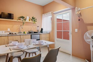 A modern kitchen with a dining table set for four, a microwave, and a variety of kitchen appliances. - Damián Carmona by Homirent (Queretaro)