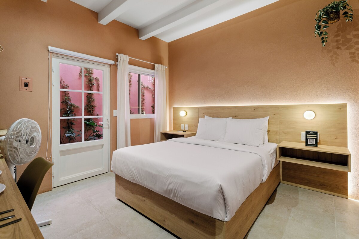 A bedroom with a bed, bedside tables, and a window with curtains.