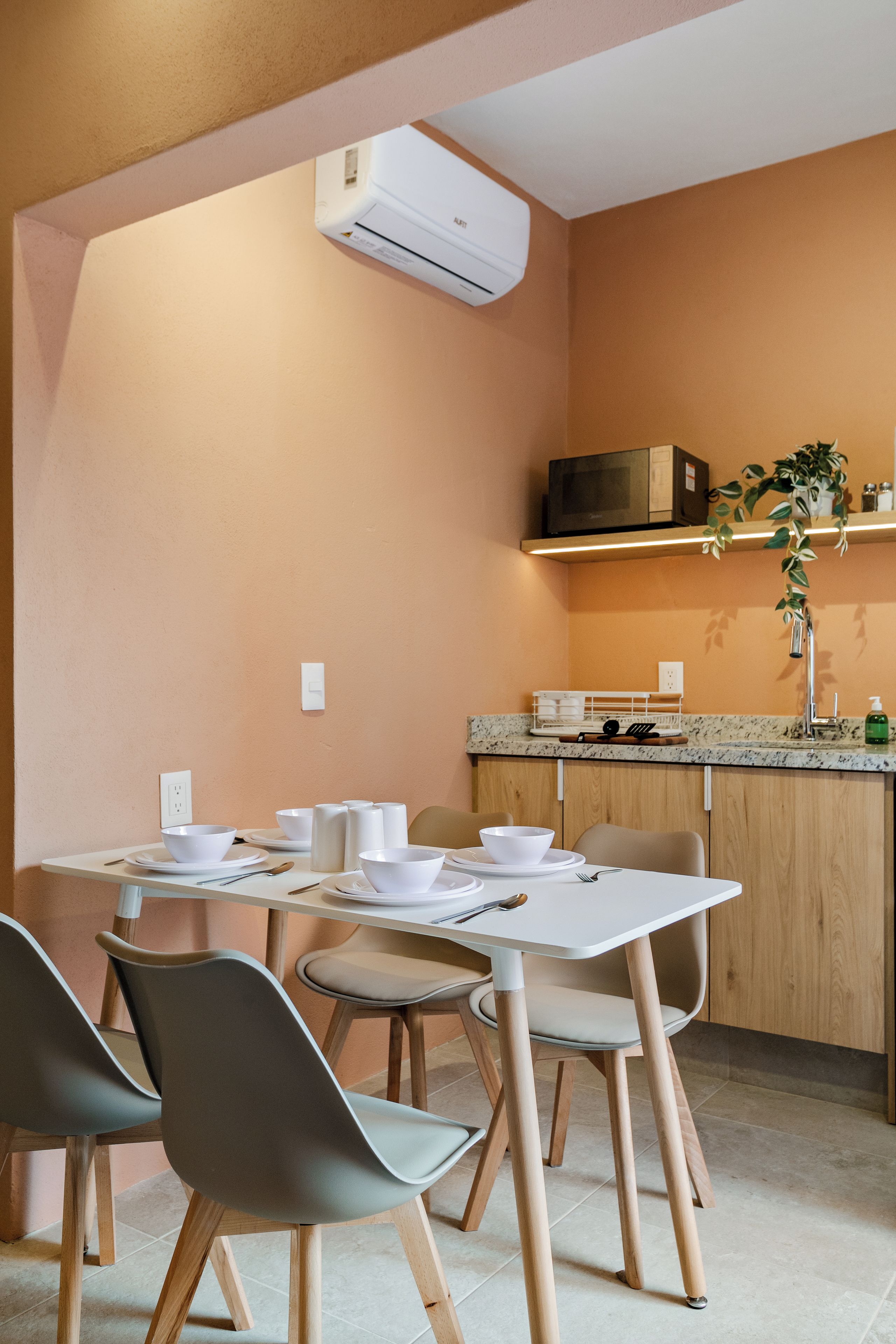 A modern kitchen with a dining area, featuring a microwave, sink, and potted plant.