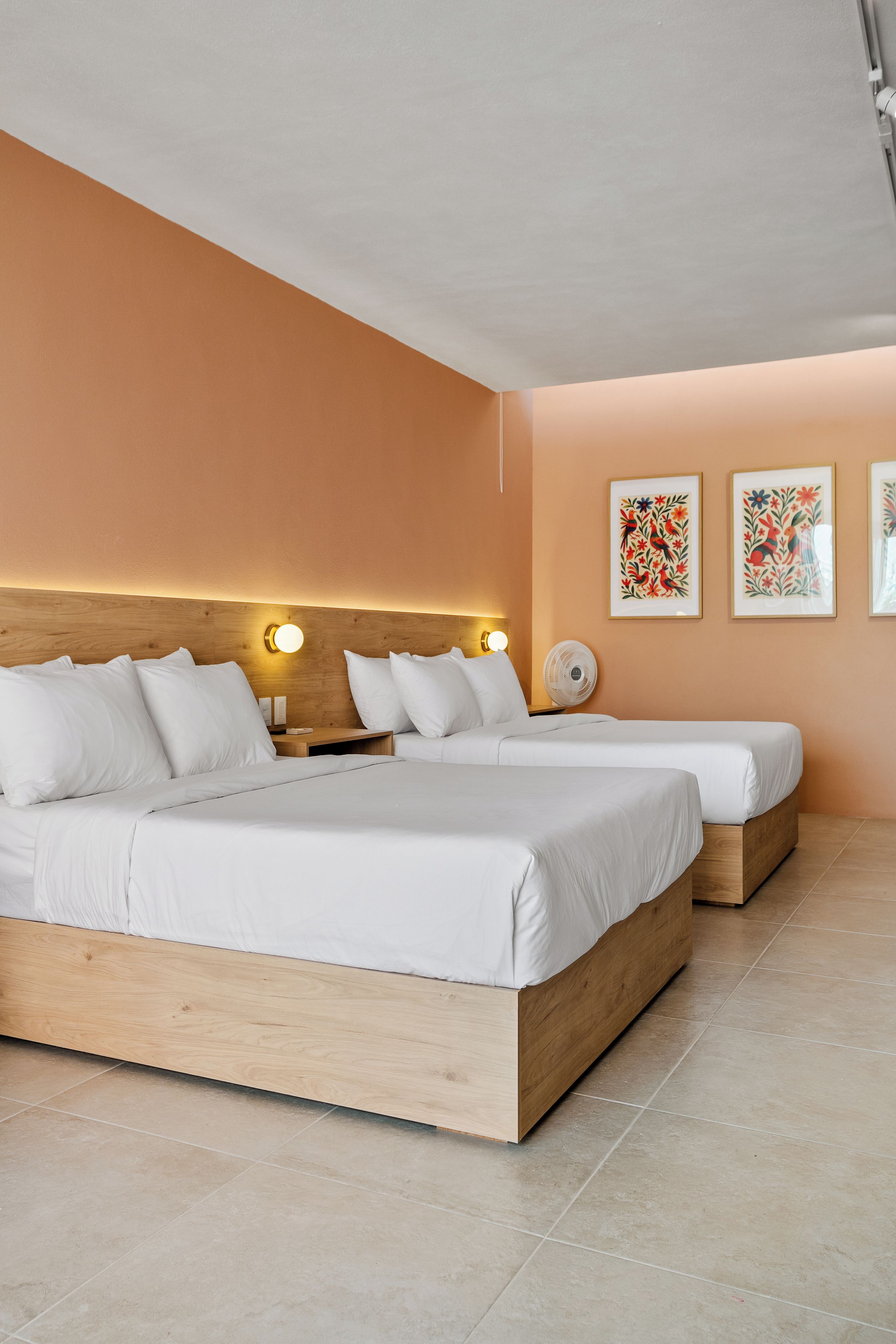 A modern bedroom with a large bed, bedside tables, and wall-mounted artwork.