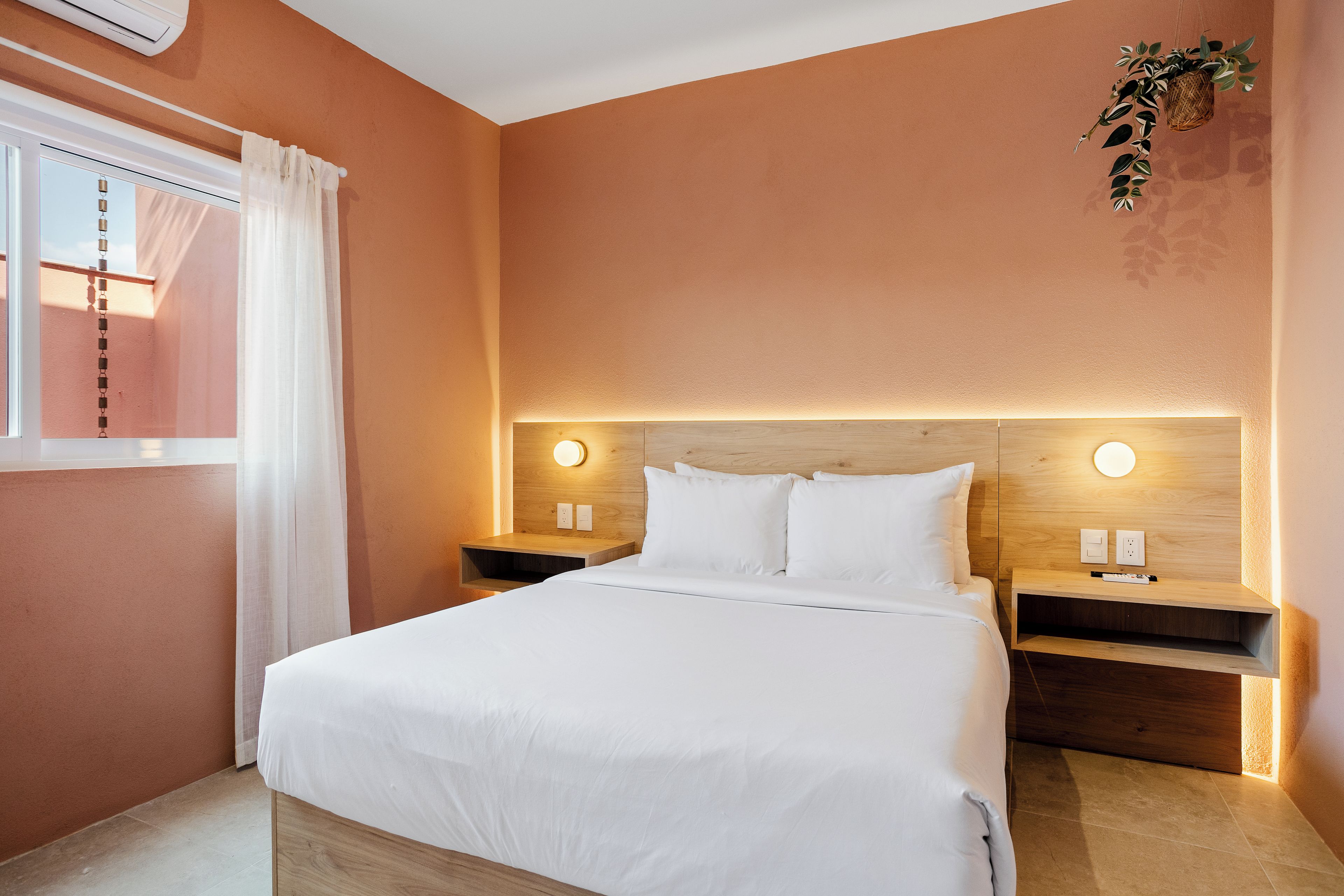 Une chambre d’hôtel avec un lit, des tables de chevet et un luminaire fixé au mur.