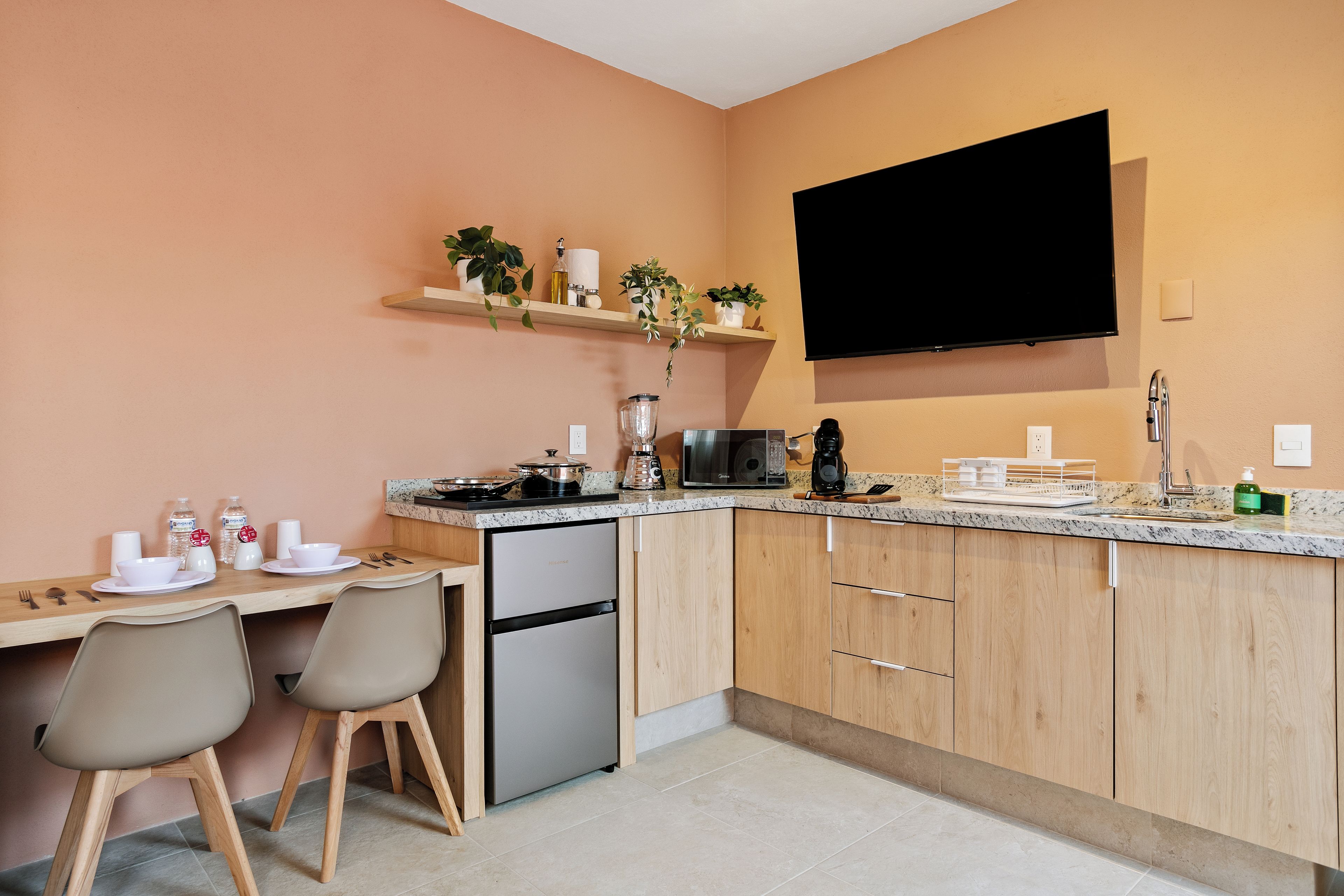 A compact kitchen with a built-in refrigerator, a microwave, and a coffee maker.