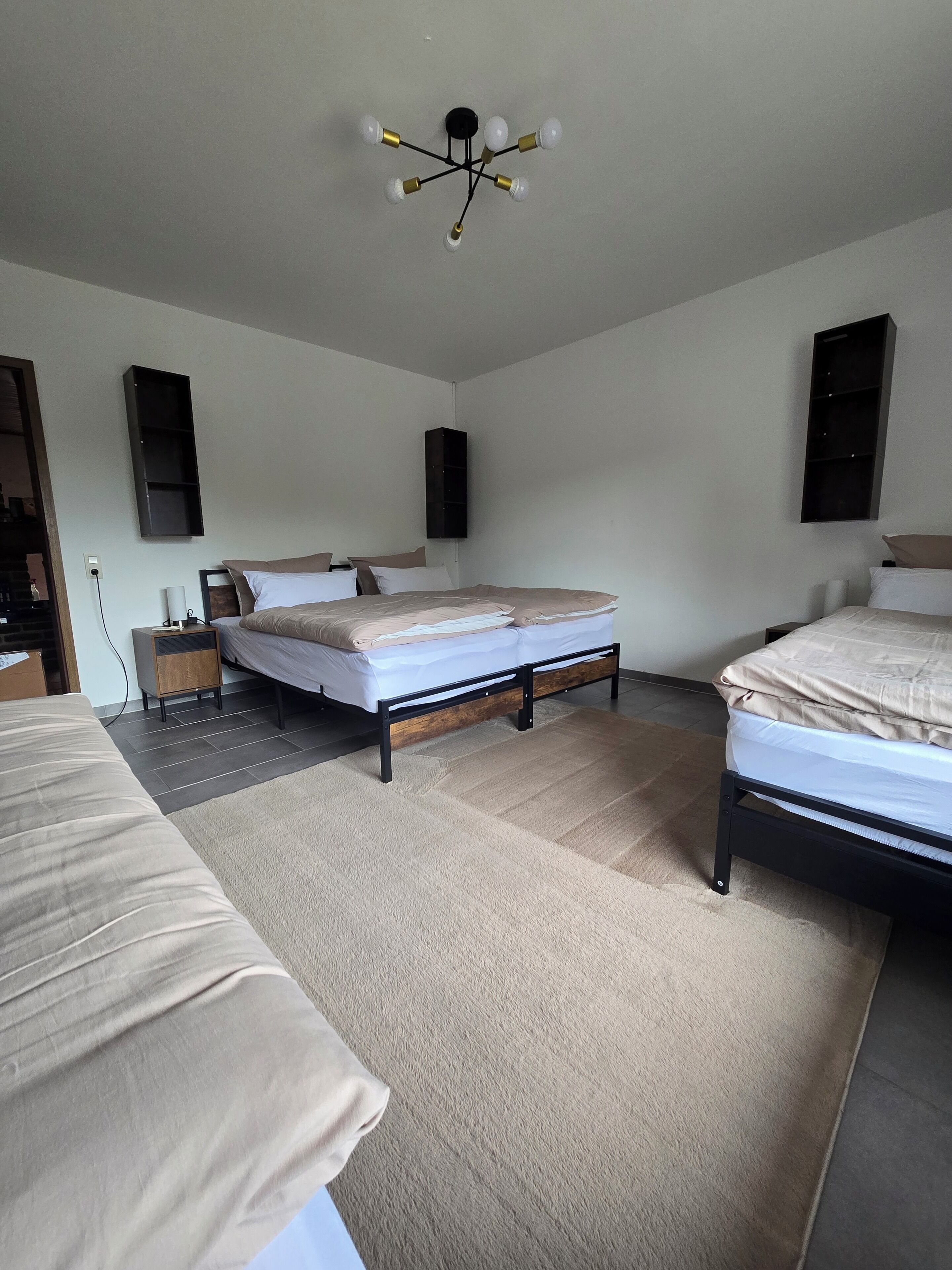 A bedroom with two beds, a ceiling light fixture, and built-in shelves.