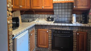 A kitchen with wooden cabinets, a stove, an oven, a refrigerator, and a microwave.