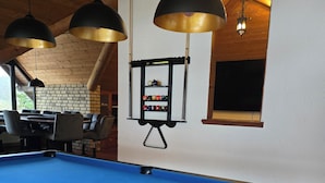 A pool table with a blue felt surface, a billiards rack, and three pendant lights.
